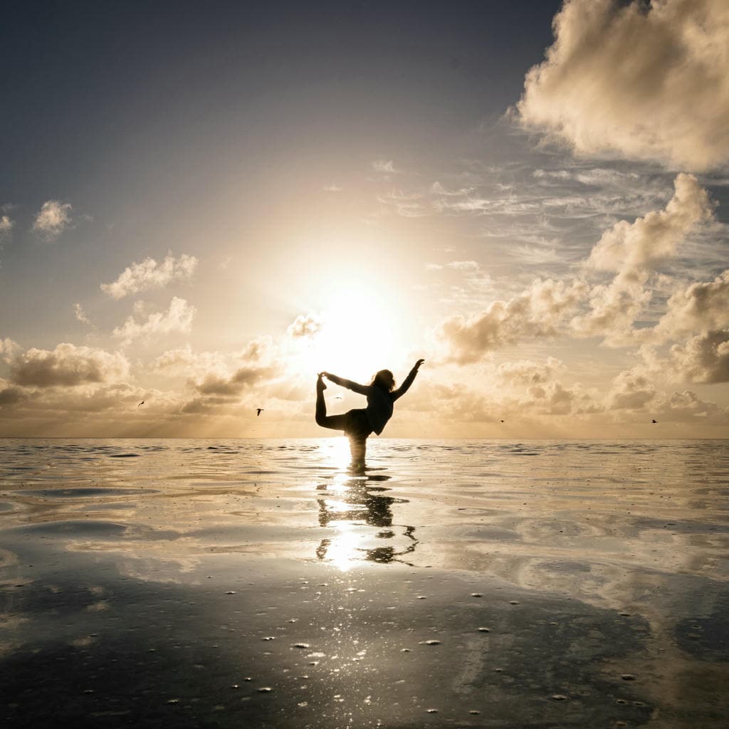 Silhouette yoga pose at ocean sunset.