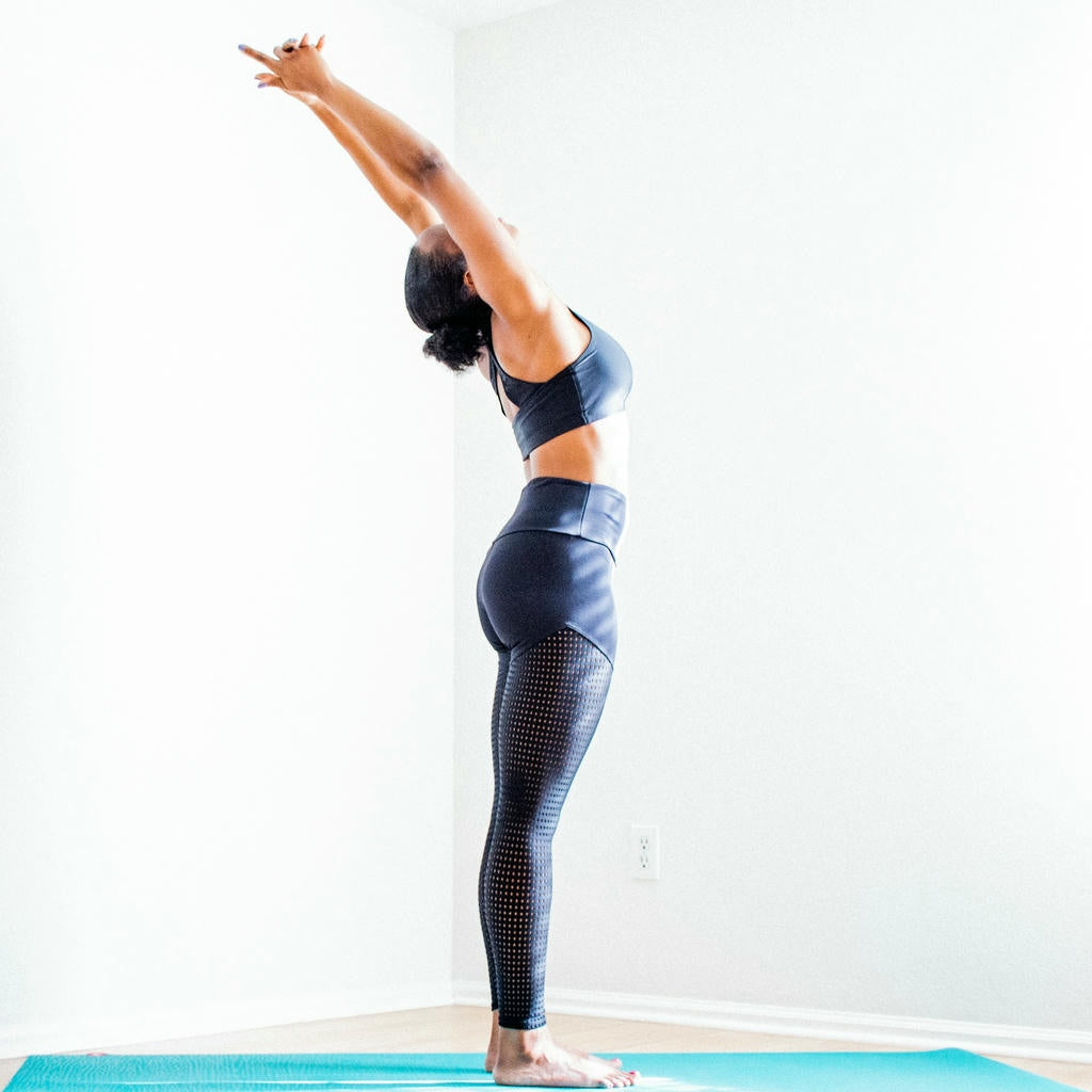 Person stretching with arms raised on blue mat.
